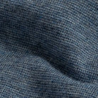A close-up of a heathered blue knit fabric texture with a fine ribbed pattern and soft folds.