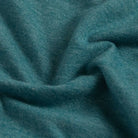 A close-up of draped teal blue fabric with a soft, slightly heathered texture.