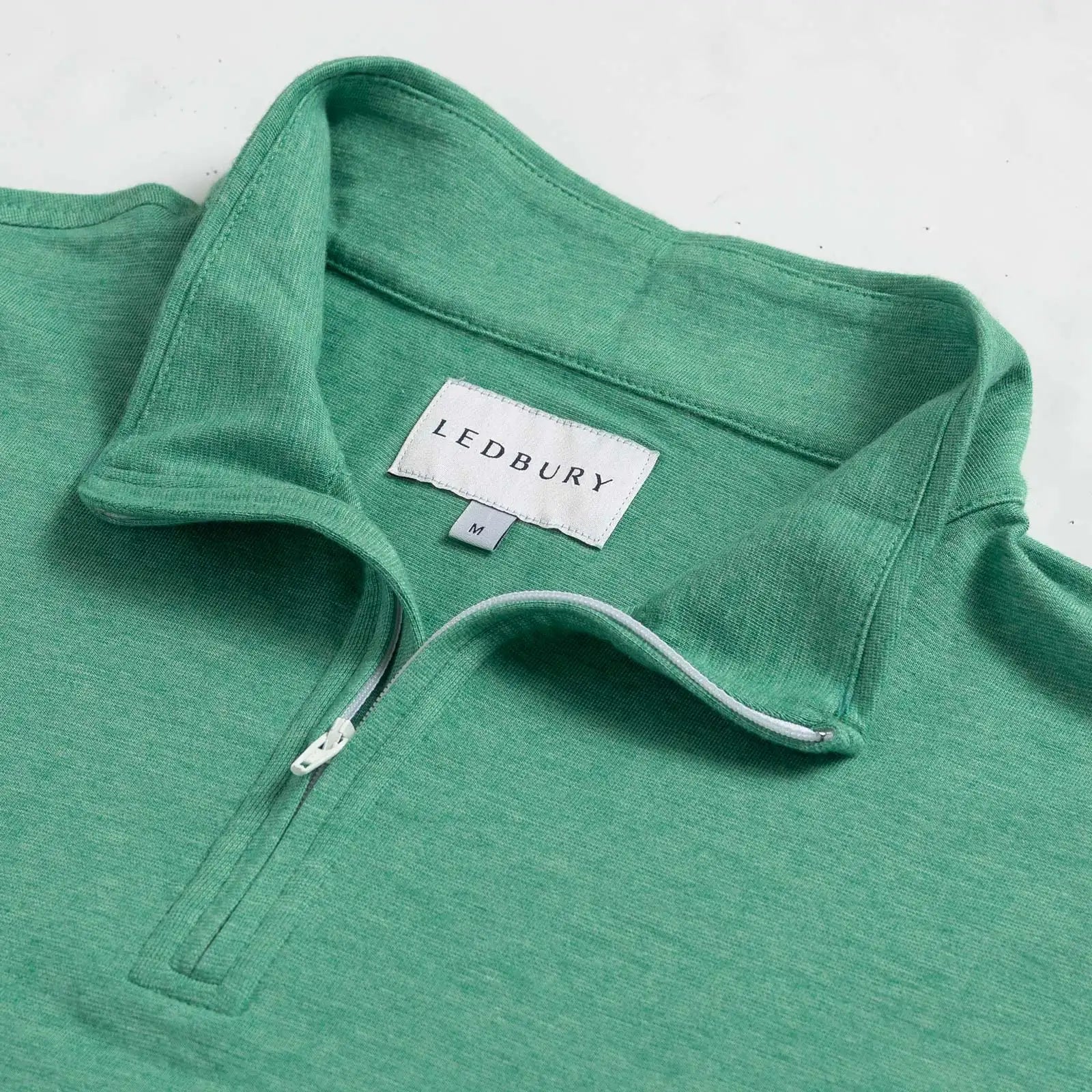Close-up of quarter-zip collar and Ledbury label on Freeman Sport Quarter Zip in Parakeet Green