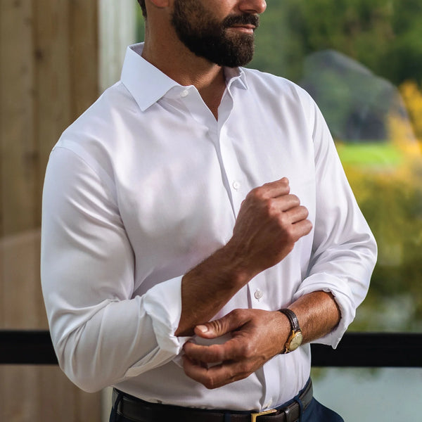Man wearing a button down non iron white dress shirt by Ledbury. He is standing in front of a window inside. 