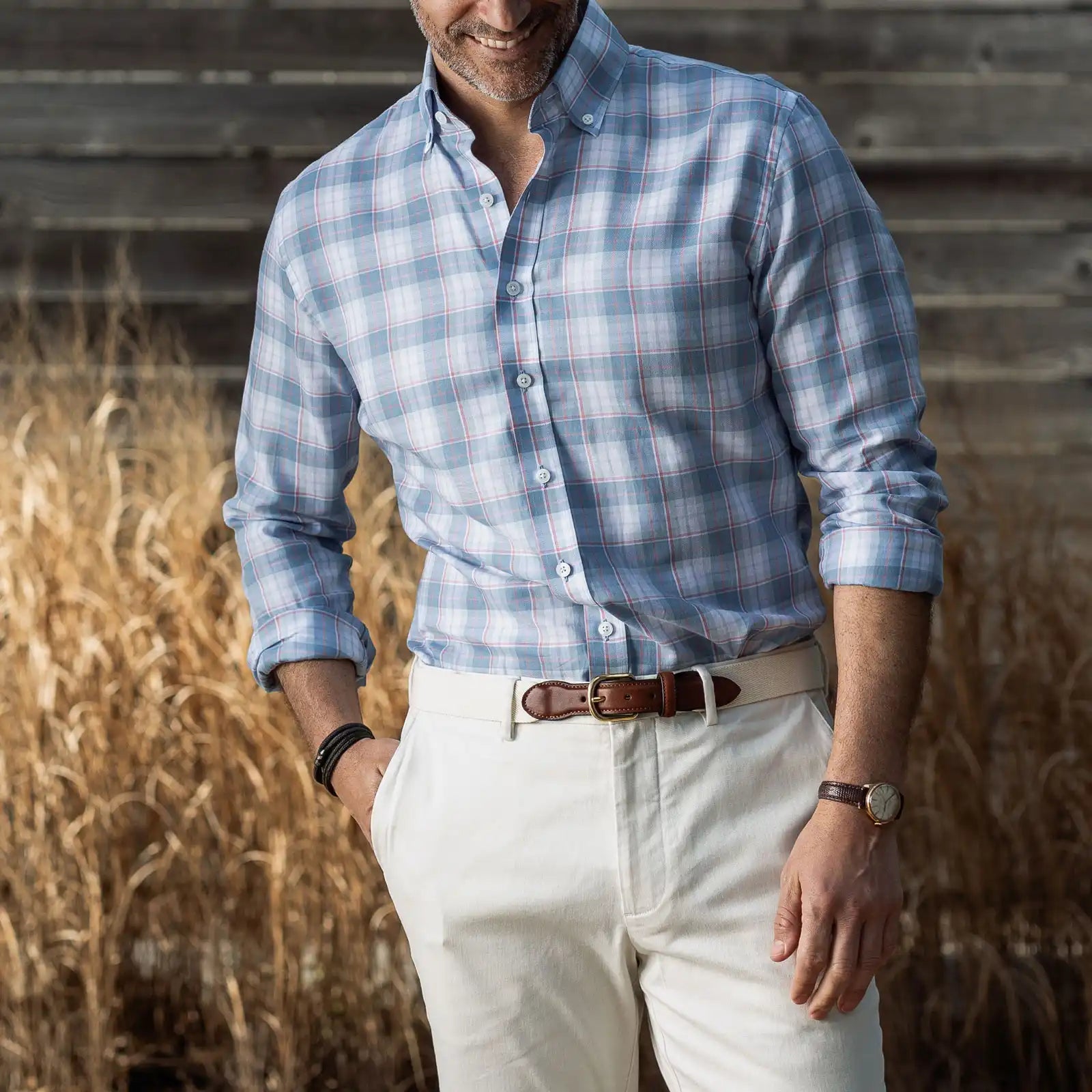 Man wearing a lightweight blue, pink and white plaid shirt with stone khakis
