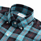Close-up of Ledbury Blue Albini Olson Plaid shirt collar and button placket detail, teal and navy plaid fabric
