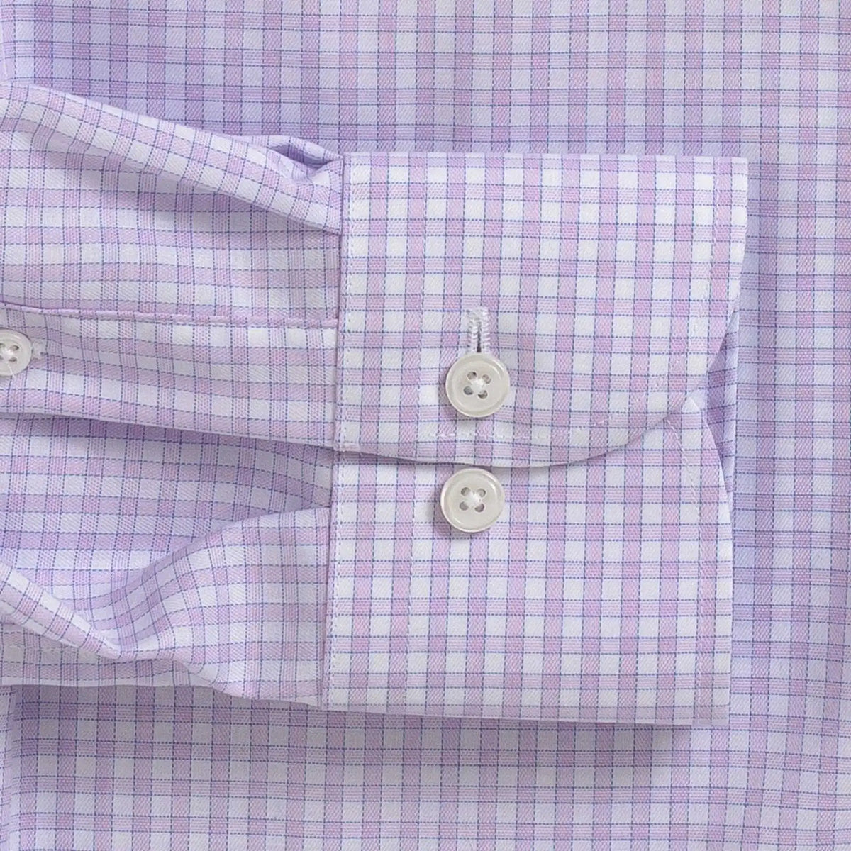Close-up of a lavender and white gingham checkered dress shirt cuff with two white buttons.