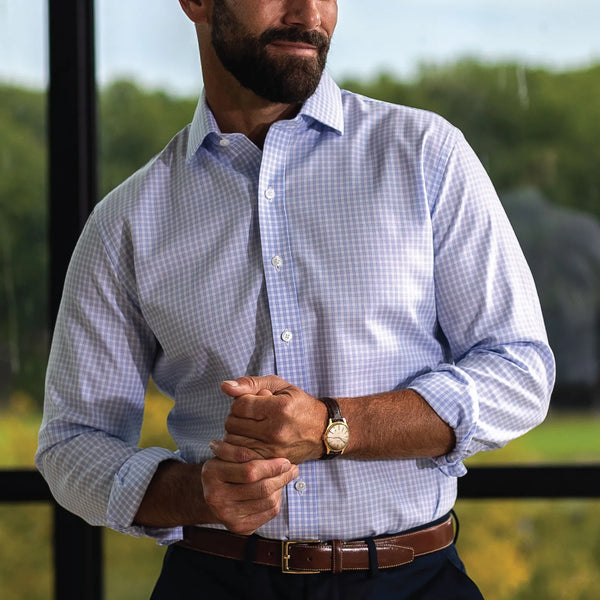Man wearing a light blue checked dress shirt by Ledbury, standing in front of a window. 