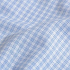 A close-up of light blue and white gingham fabric with a soft, draped fold showing the woven texture.