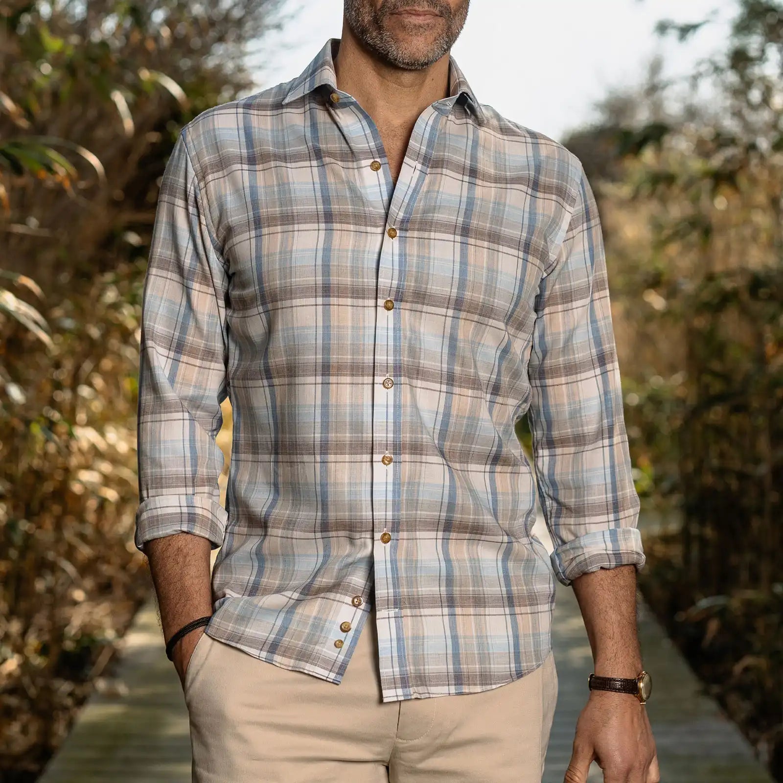 Man wearing a plaid shirt outdoors with a natural background