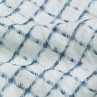 Close-up of a textured Italian linen fabric with a check pattern in white and blue.