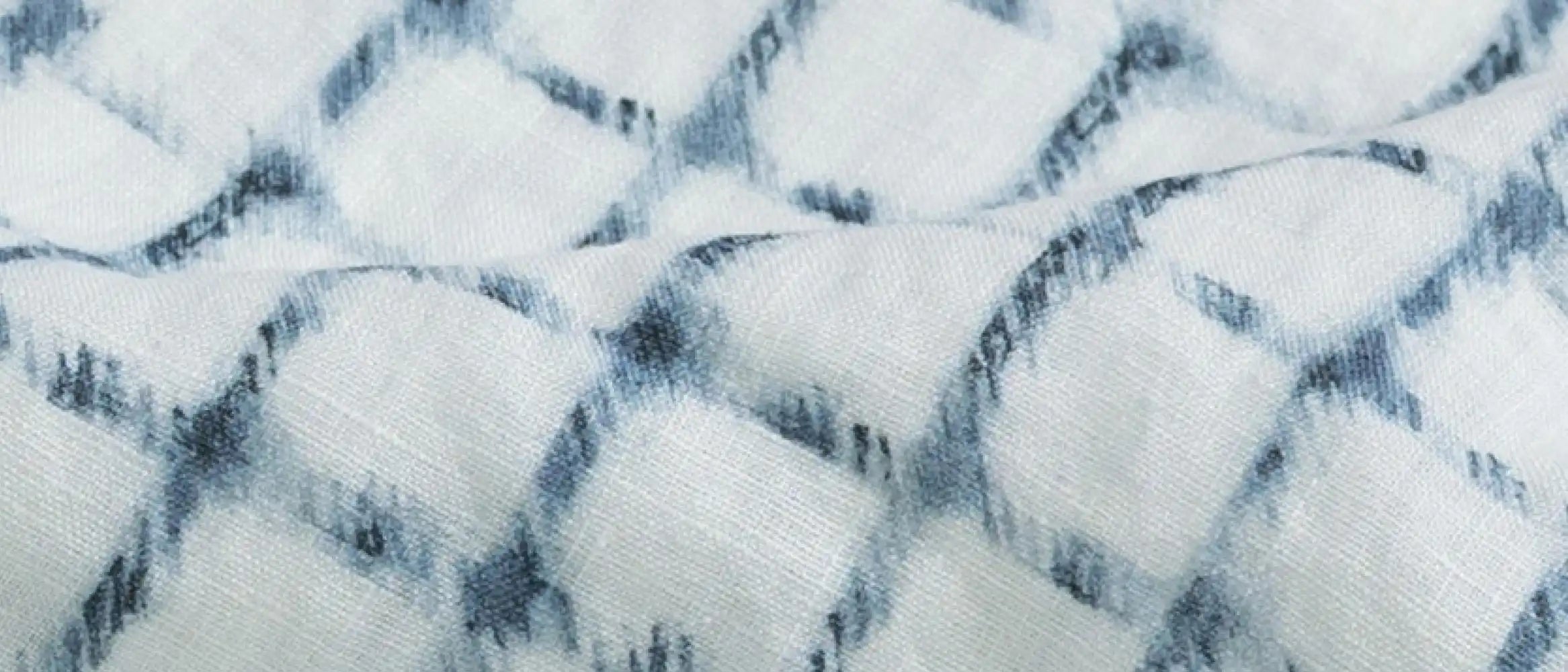 Close-up of a textured Italian linen fabric with a check pattern in white and blue.