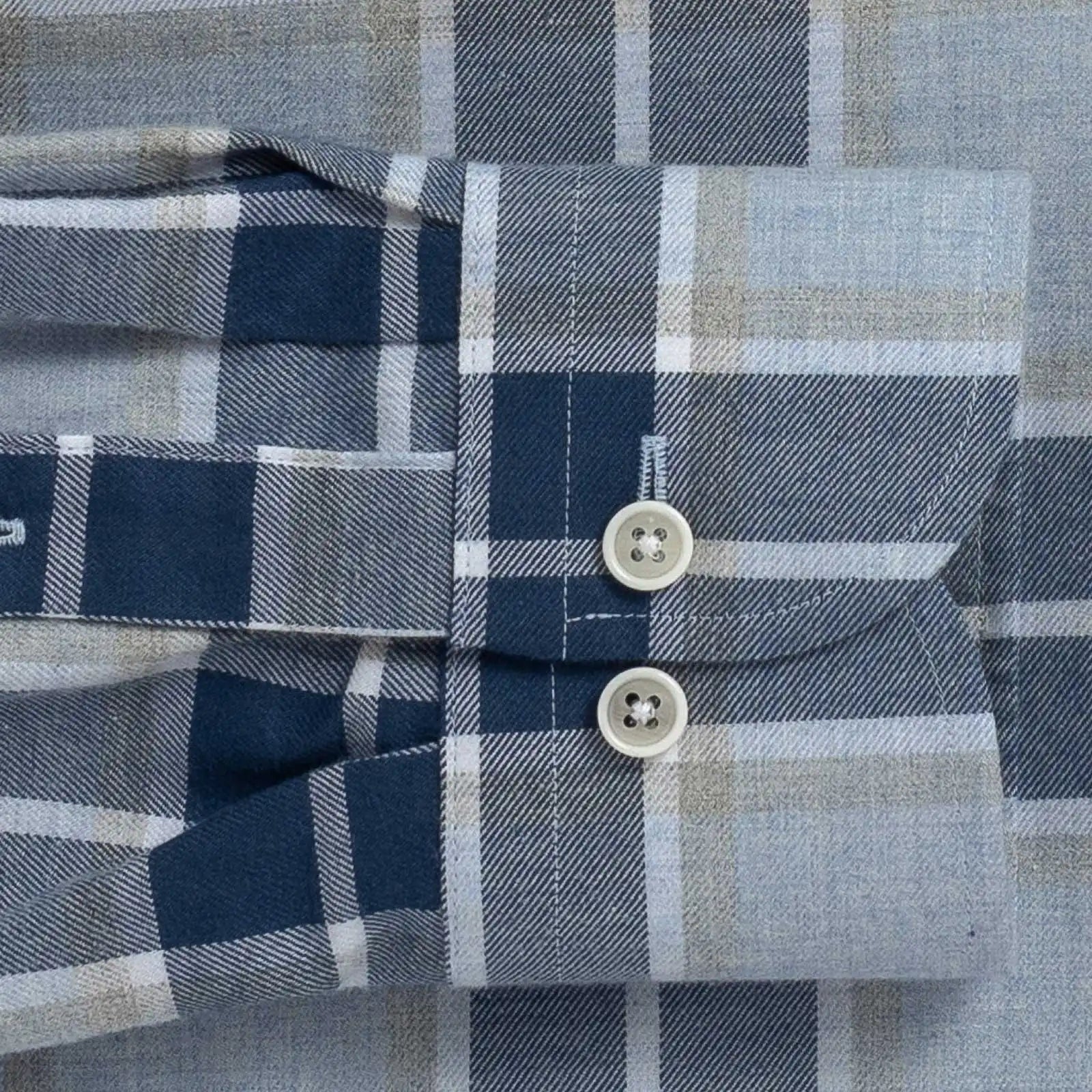 Close-up of the sleeve of a plaid shirt with buttons on a checkered pattern