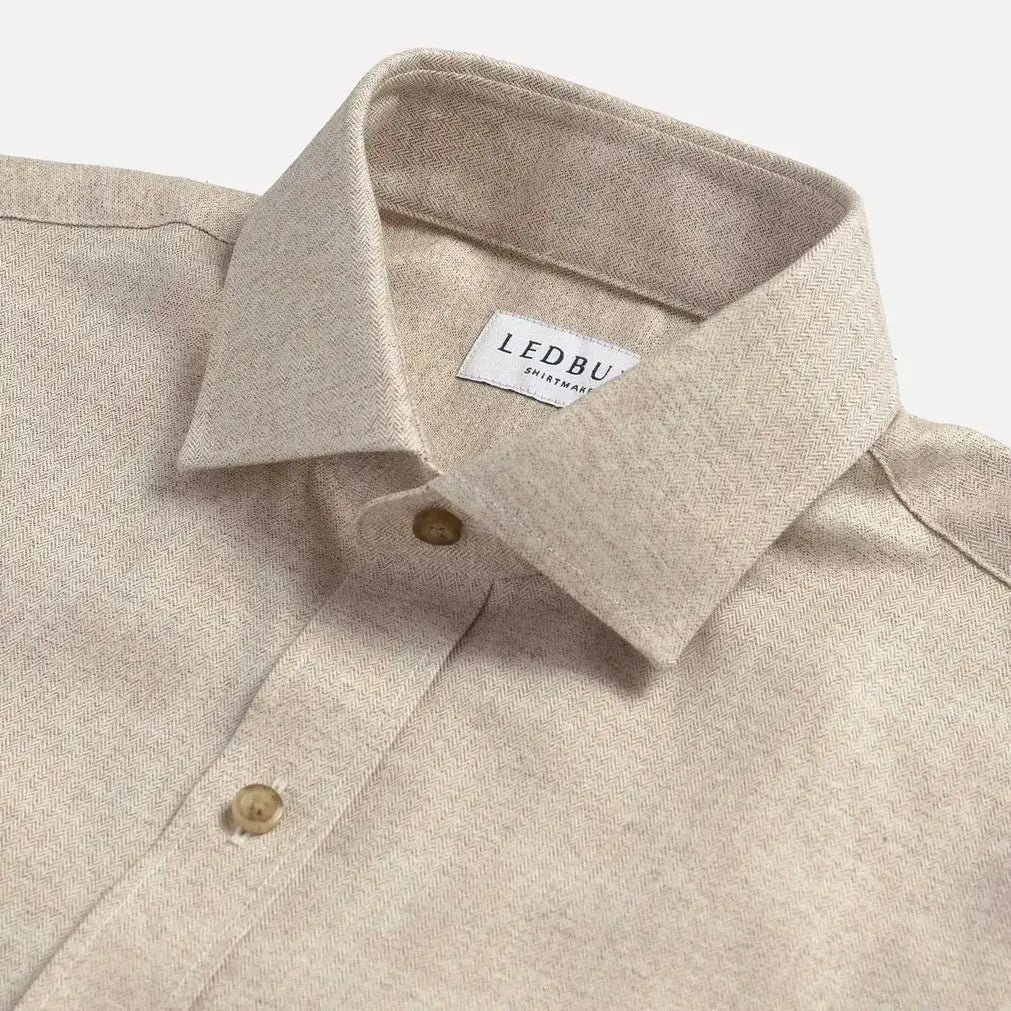 Close-up of an oatmeal colored shirt with a collar and button details