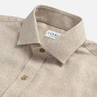 Close-up of an oatmeal colored shirt with a collar and button details
