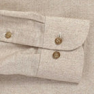 Close-up of a beige textured herringbone shirt with buttons 
