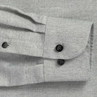 Close up of the sleeve of a grey small scale herringbone dress shirt with black buttons