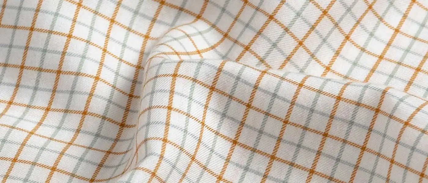 Close-up of checkered fabric with orange and gray lines on a white background