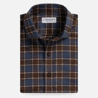 A folded men's button-up shirt by Ledbury, featuring a classic plaid pattern in dark brown, slate blue, and thin cream stripes, set against a plain light gray background.