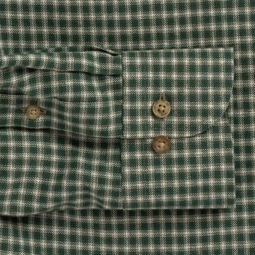 Close-up of a green and white gingham plaid shirt cuff with two brown buttons.