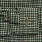 Close-up of a green and white gingham plaid shirt cuff with two brown buttons.