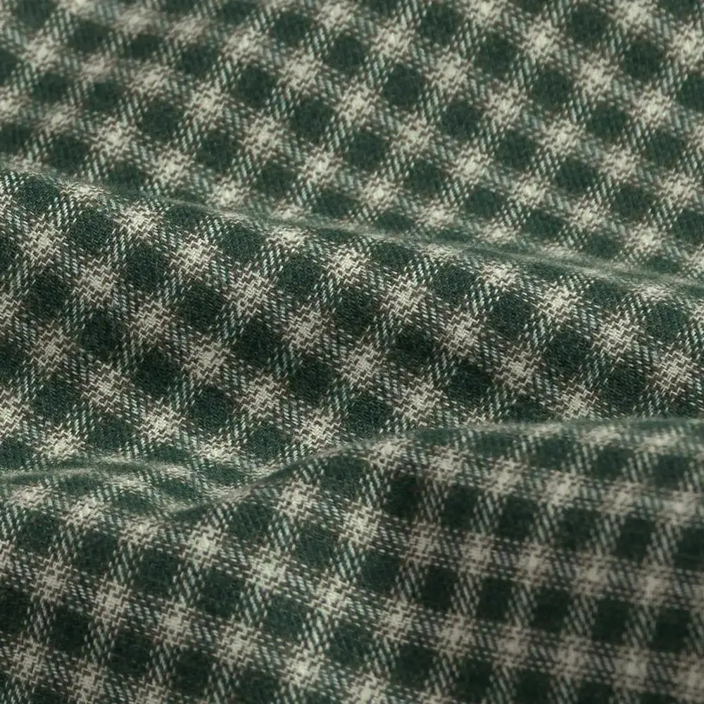 A close-up of a dark green and off-white plaid fabric with a soft, draped texture.