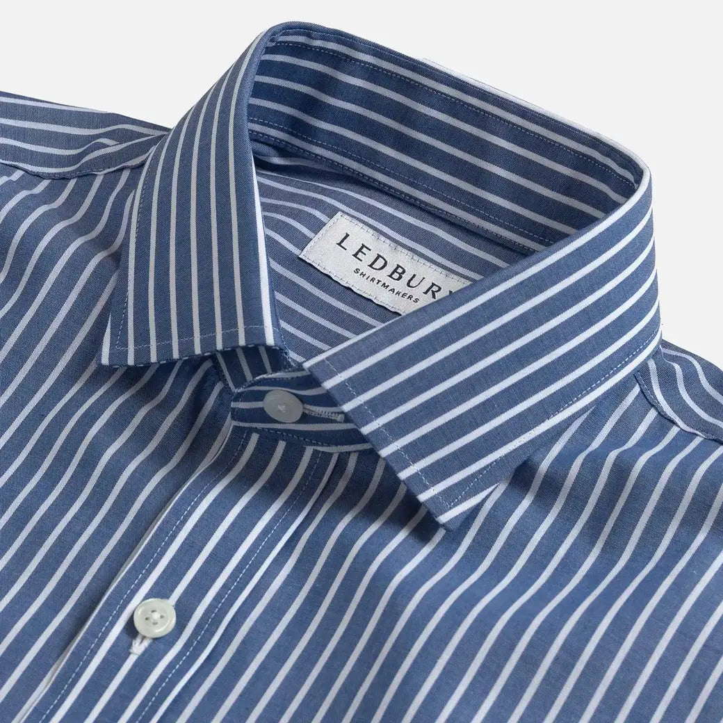 Close-up of a LEDBURY men's dress shirt with a blue and white vertical stripe pattern, featuring a classic collar and white buttons.