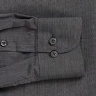 Close-up of a dark gray textured fabric shirt cuff with two dark buttons and a buttoned pocket flap.