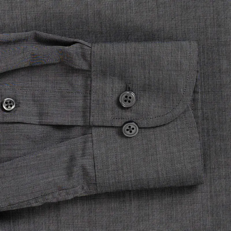 Close-up of a dark gray textured fabric shirt cuff with two dark buttons and a buttoned pocket flap.
