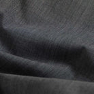 A close-up of dark charcoal gray fabric with a fine diagonal twill weave and soft folds.