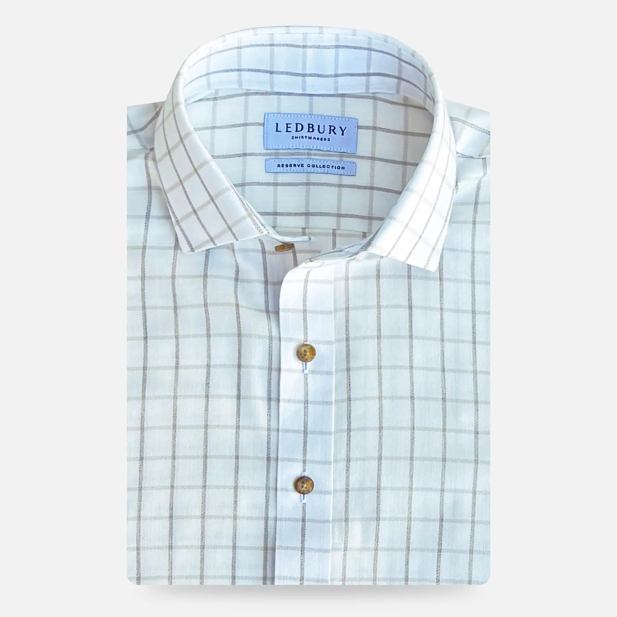 A folded light beige and white checkered dress shirt with brown buttons, featuring a visible LEDBURY brand label on the collar, set against a light gray background.