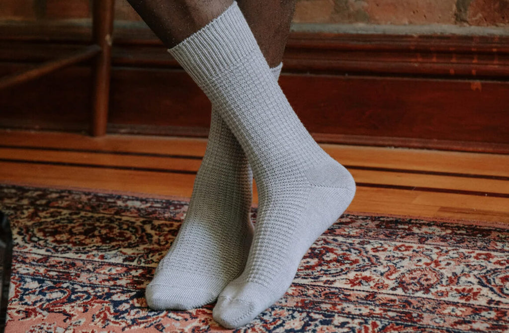 Man standing inside on a wool carpet wearing grey casual socks