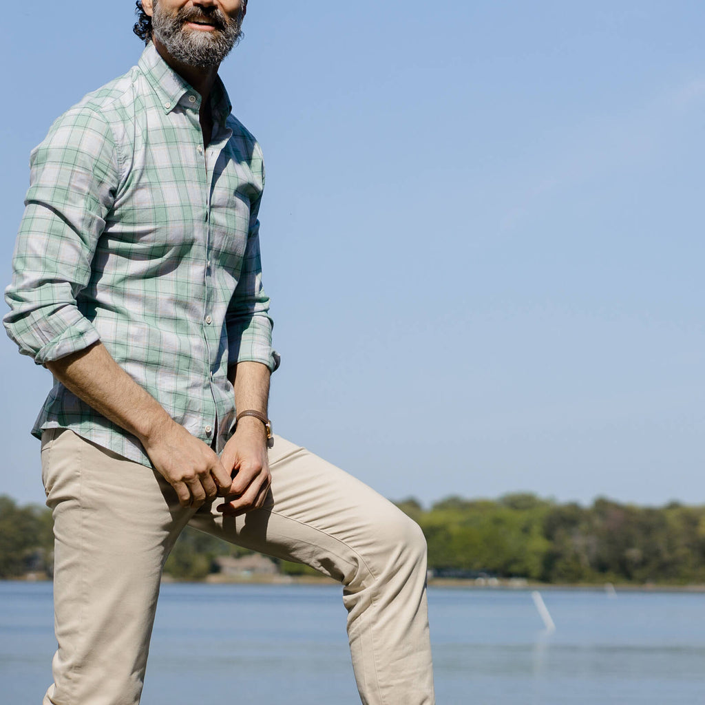 Image of a model standing on a dock wearing a button down shirt and tan chinos