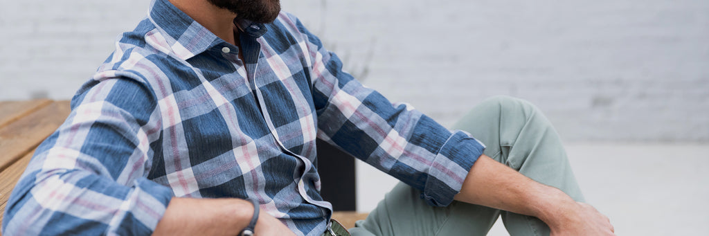 Image of a male model wearing a men's blue, pink and white summer weight plaid shirt. 
