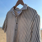 Ledbury navy and cream striped camp collar shirt hanging on a hanger at the beach