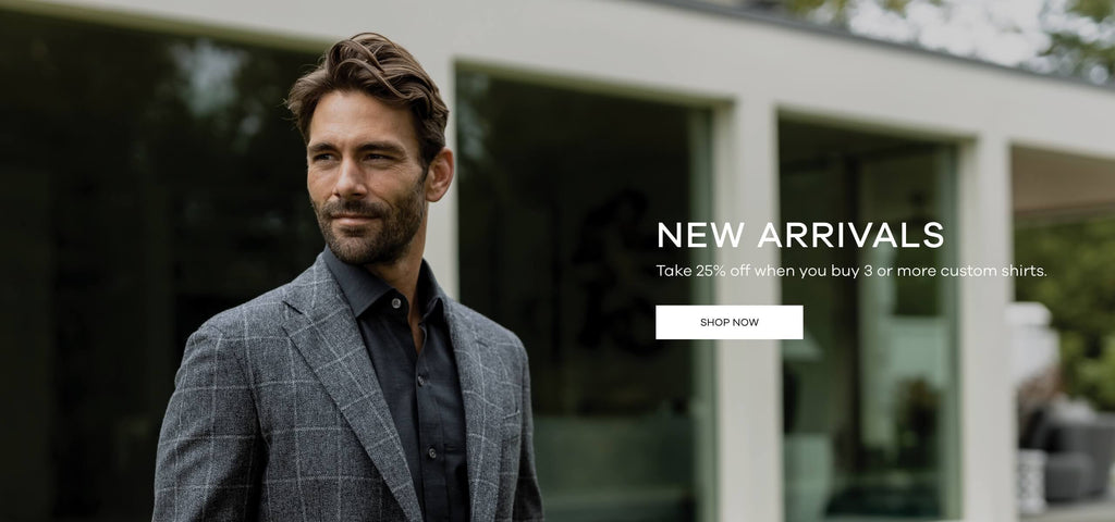 Male model standing in front of a modern home. He is wearing a charcoal grey Ledbury button down shirt and a sport coat. Text reads - New Arrivals - Take 25% off when you buy 3 or more custom shirts.