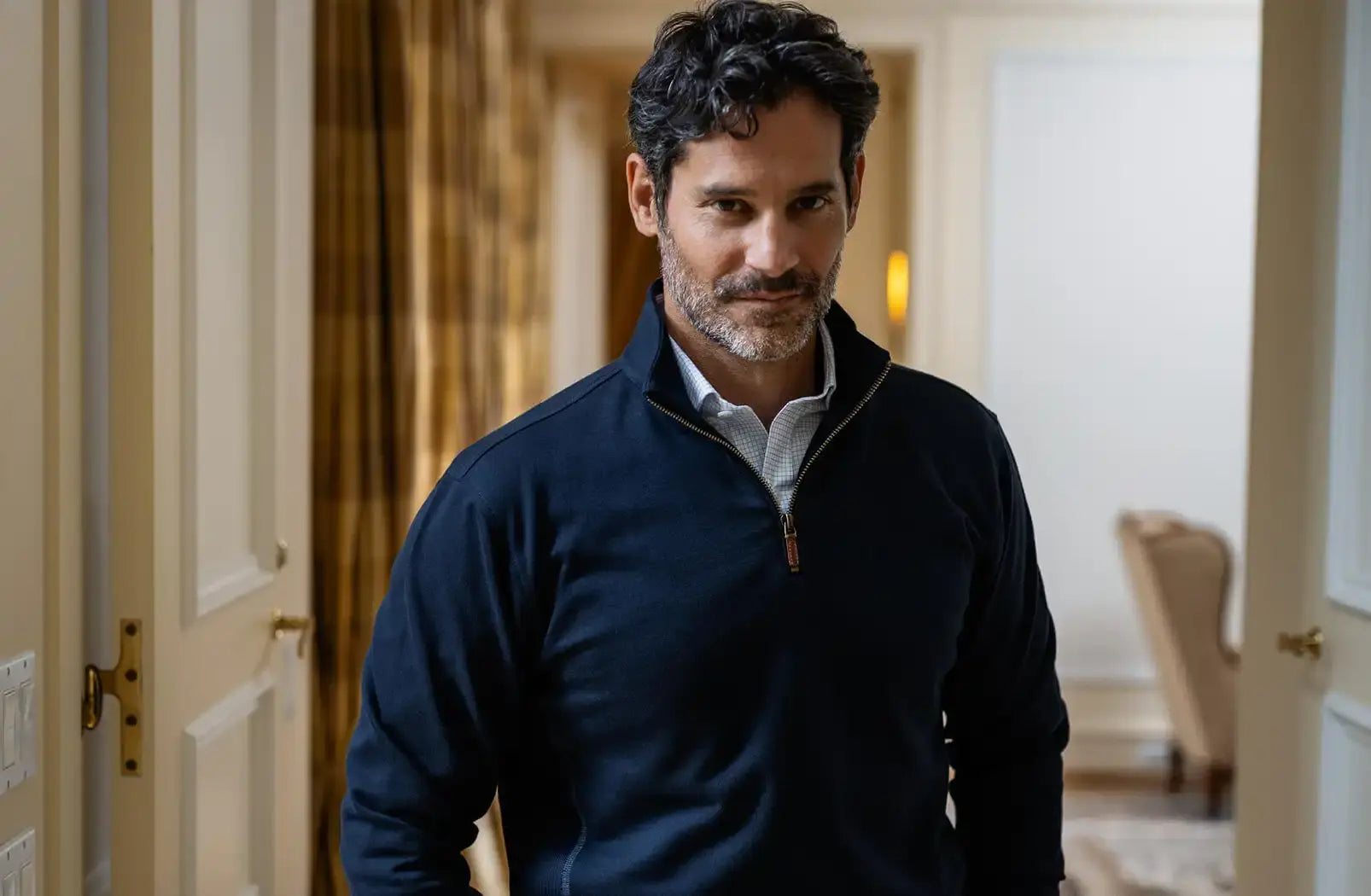 Man wearing a dark blue quarter zip in an indoor setting