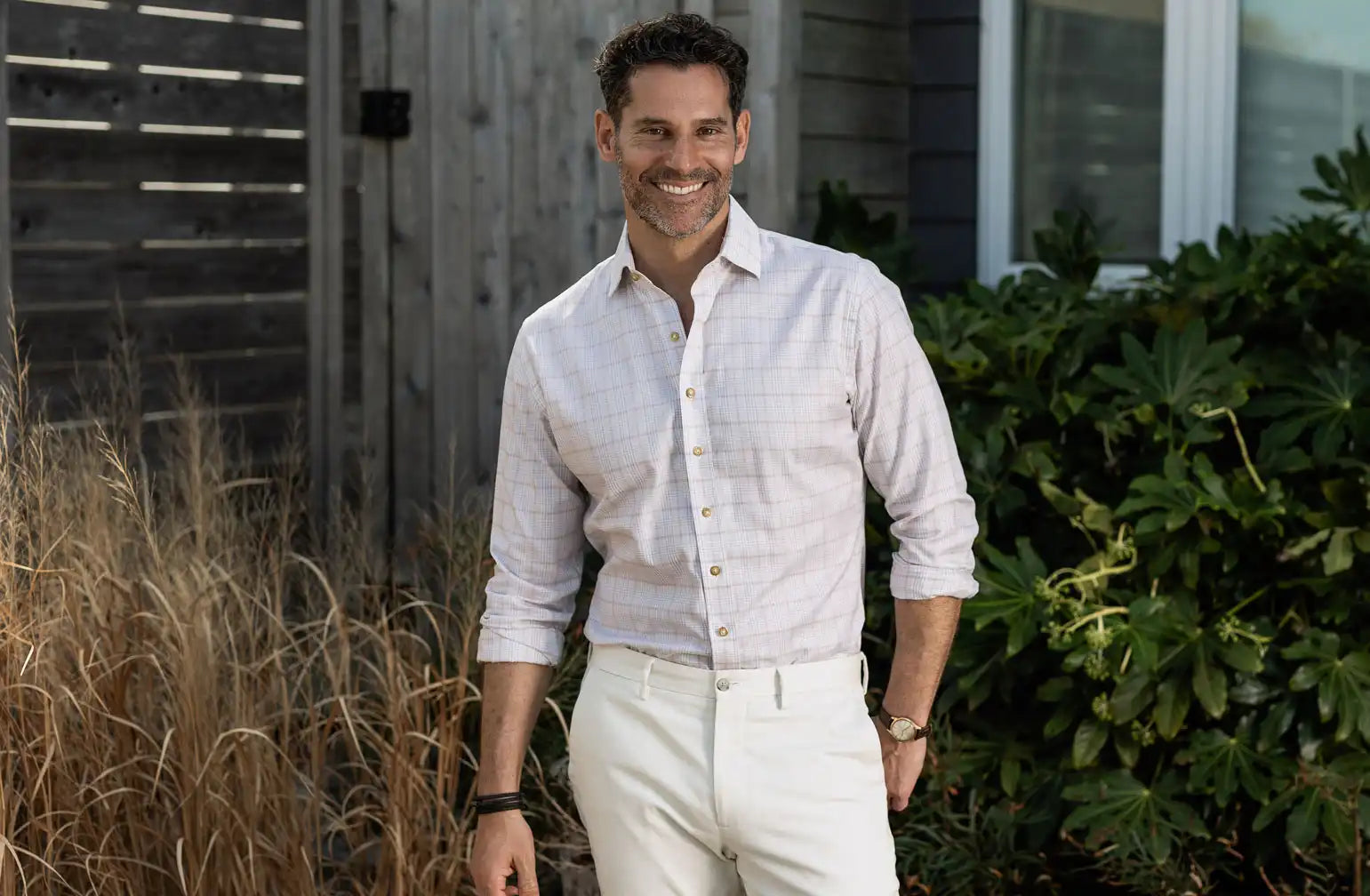 Model wearing a light tan and white check button down shirt by Ledbury