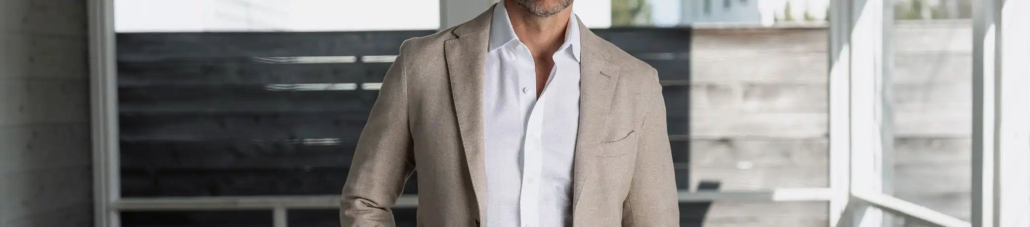 Man wearing a beige blazer over a white shirt in an outdoor setting