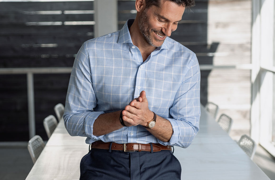 Man wearing a light blue and white checked shirt in an outdoor setting