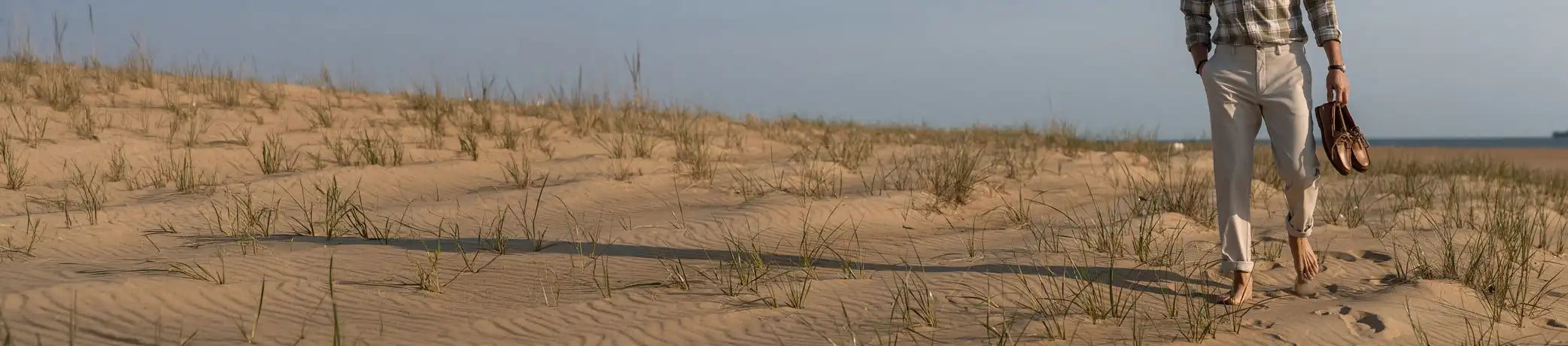 Person walking on a sandy landscape with a clear sky