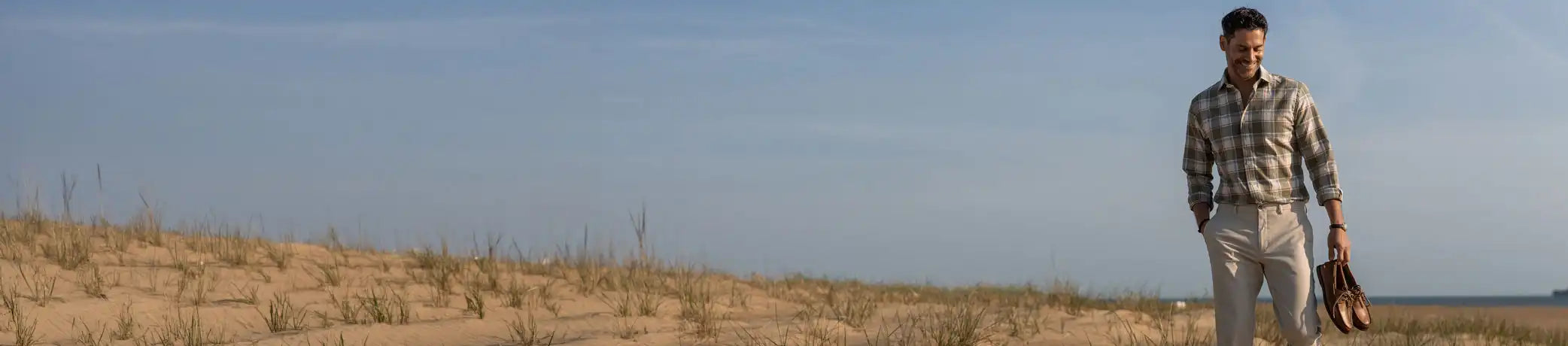 Man wearing a Ledbury olive green checked button down shirt on the beach
