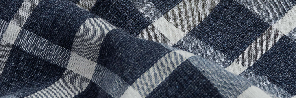Close up of the fabric of a men's navy blue and white checked cotton linen button down shirt