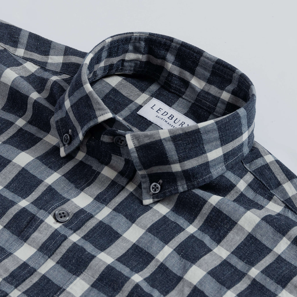 Close up of the collar of a men's navy blue and white checked cotton linen button down shirt
