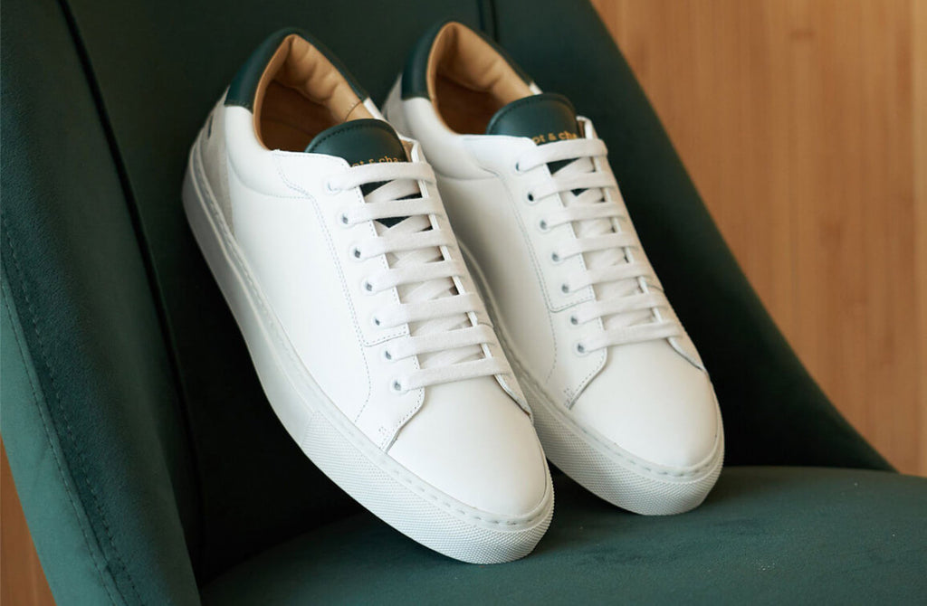 White and dark green sneakers leaning on a dark green velvet chair