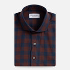 A folded men's dress shirt by Ledbury, featuring a classic checkered pattern in bordeaux red and navy blue. The shirt is neatly folded to show the collar, front button placket, and fabric texture against a clean, light gray background.