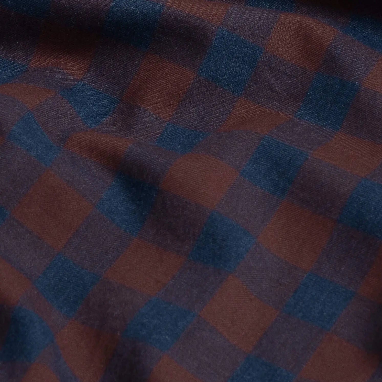 A close-up of a plaid fabric with a checkered pattern in dark blue and bordeaux red.