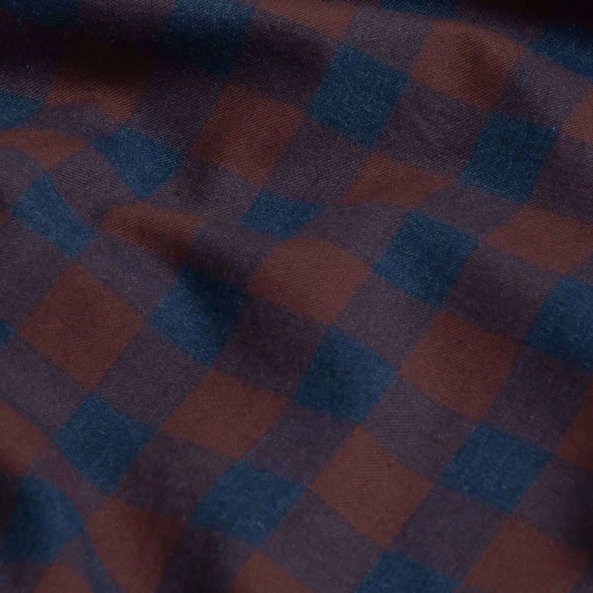 A close-up of a plaid fabric with a checkered pattern in dark blue and bordeaux red.