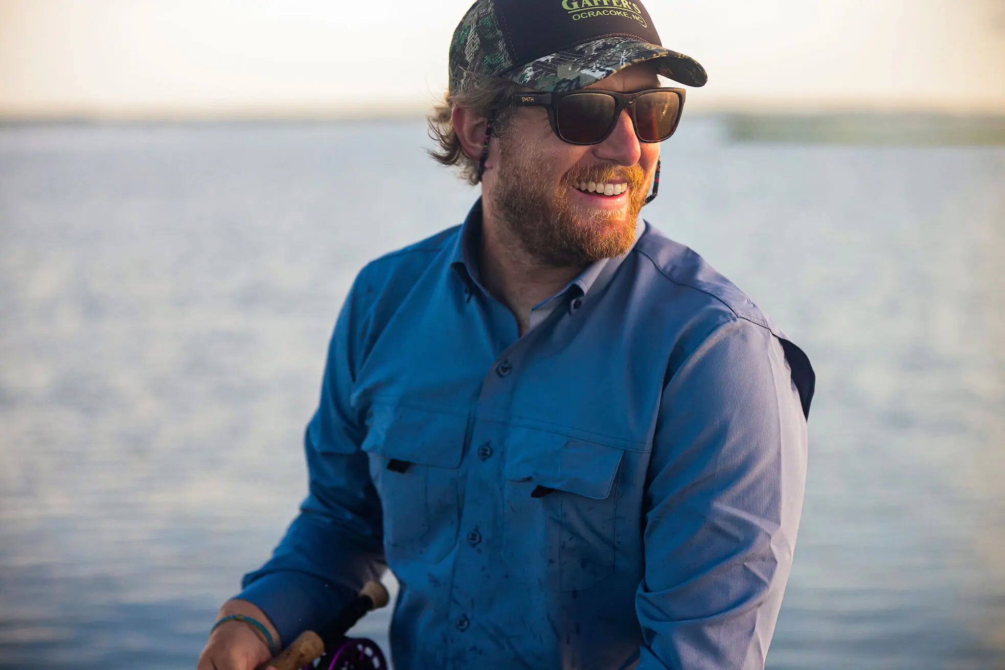 Man wearing sunglasses and a Ledbury fishing shirt by a body of water
