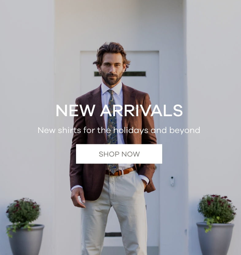 A man wearing a white dress shirt and a brown sports coat in front of a white house. The image says "New Arrivals. New Shirts for the holidays and beyond. Shop Now."
